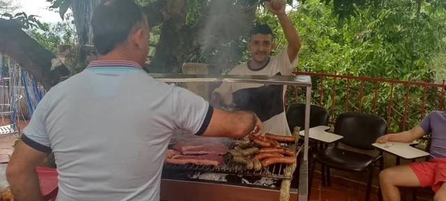 Personas cocinan y comparten alrededor de una parrilla en la finca